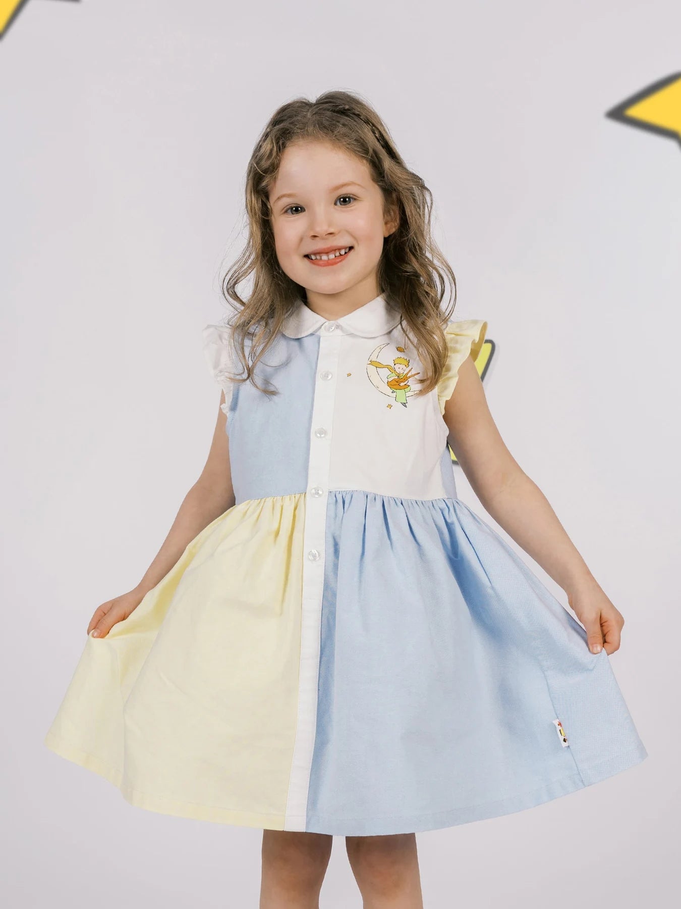 Girl smiling in the blue and yellow colour-blocked Le Petit Prince dress.