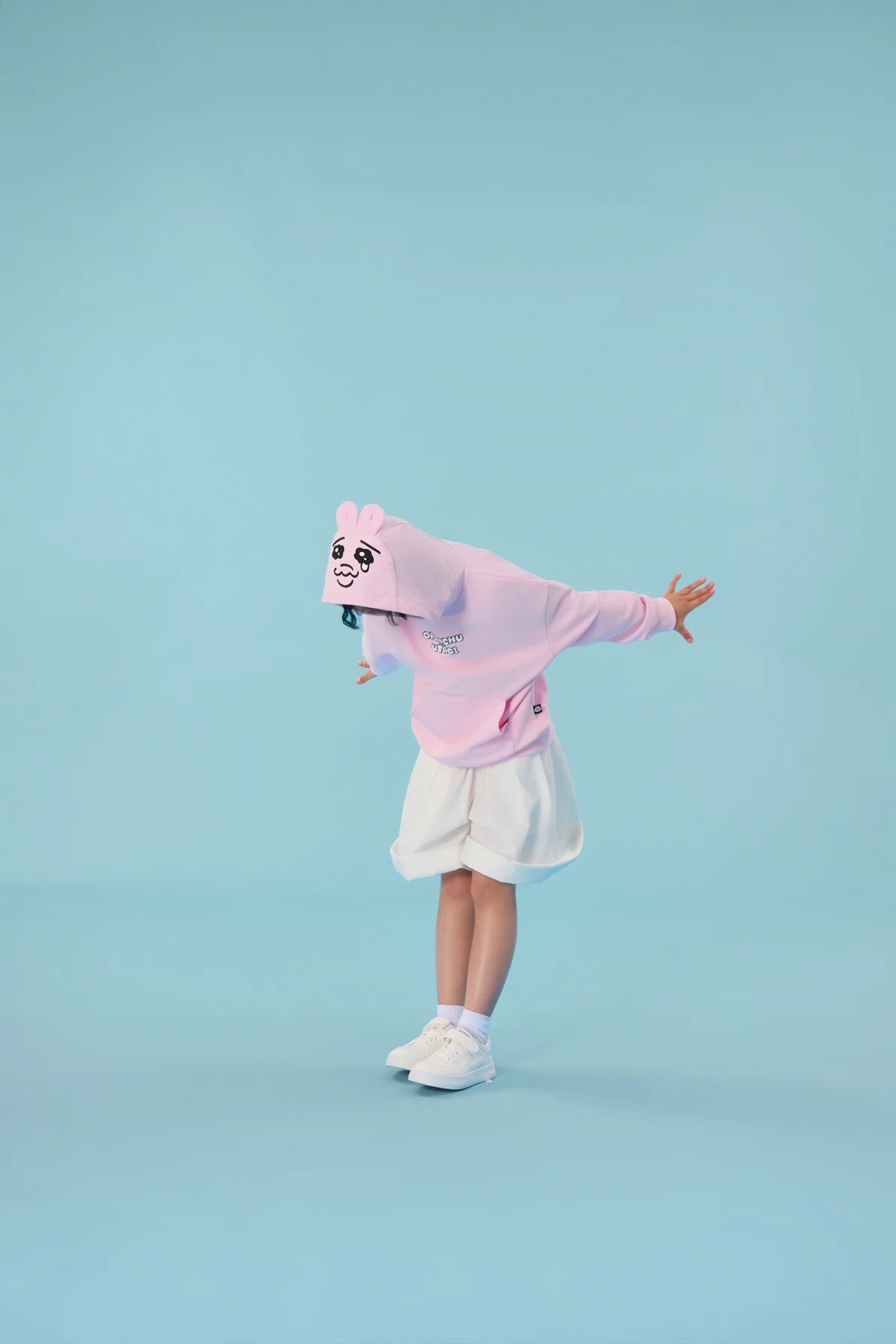 A pink bunny-ear hood and embroidered expression give the sweatshirt its playful personality.