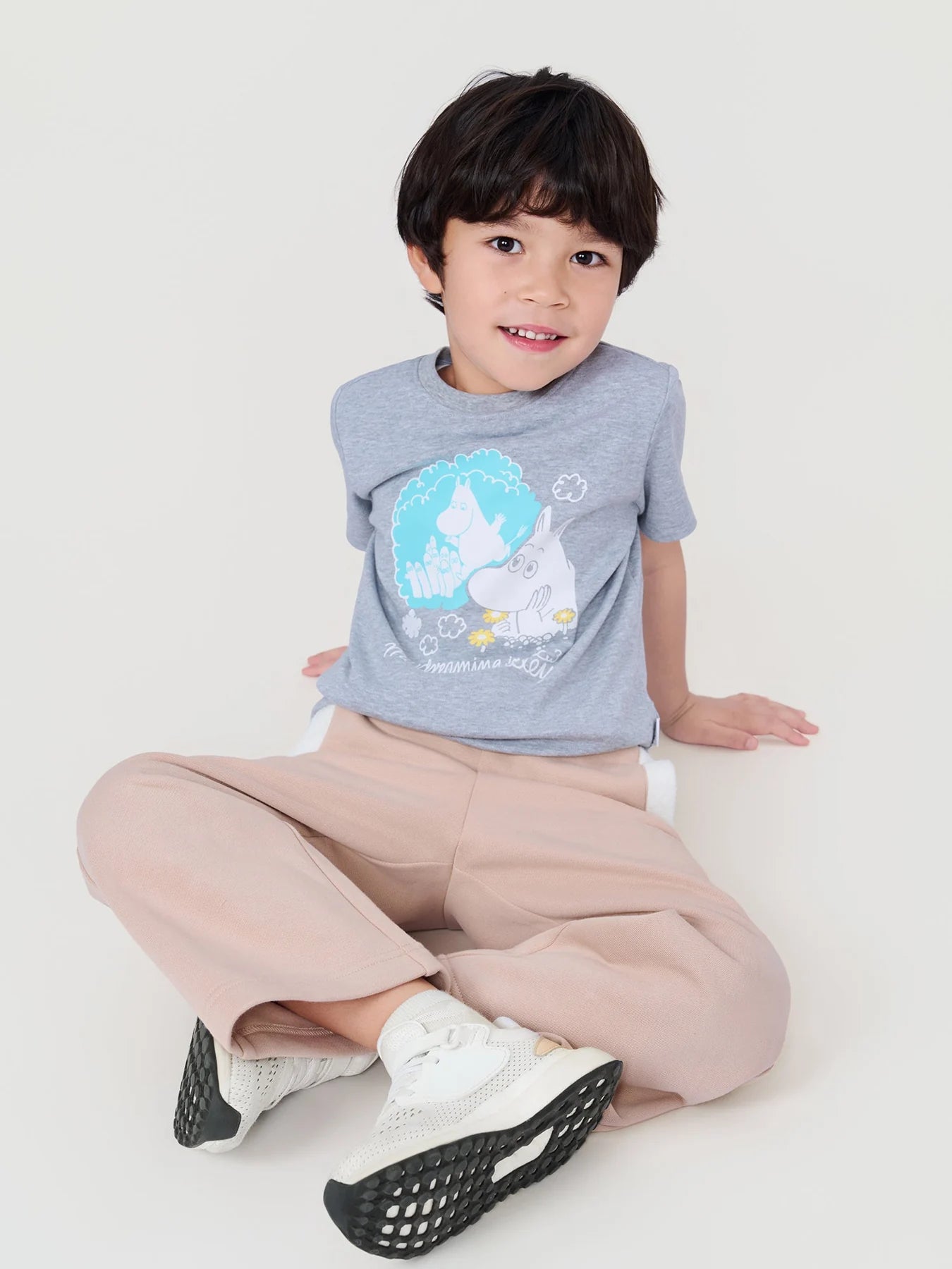 Boy seated wearing the grey Daydreaming in Moominvalley T-shirt.