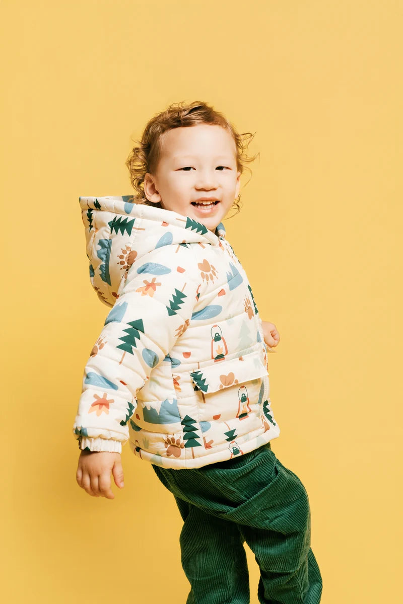 A smiling child in a printed jacket and green trousers. Face of Vauva 2025.