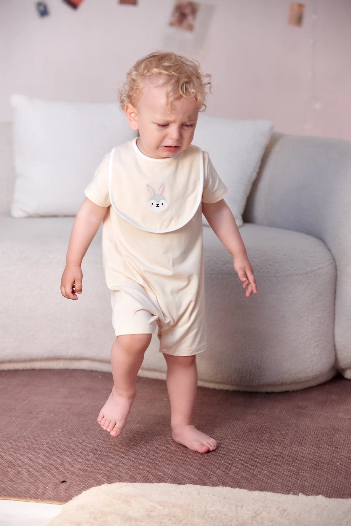 A toddler explores in the beige bunny graphic romper from the four-piece gift set.