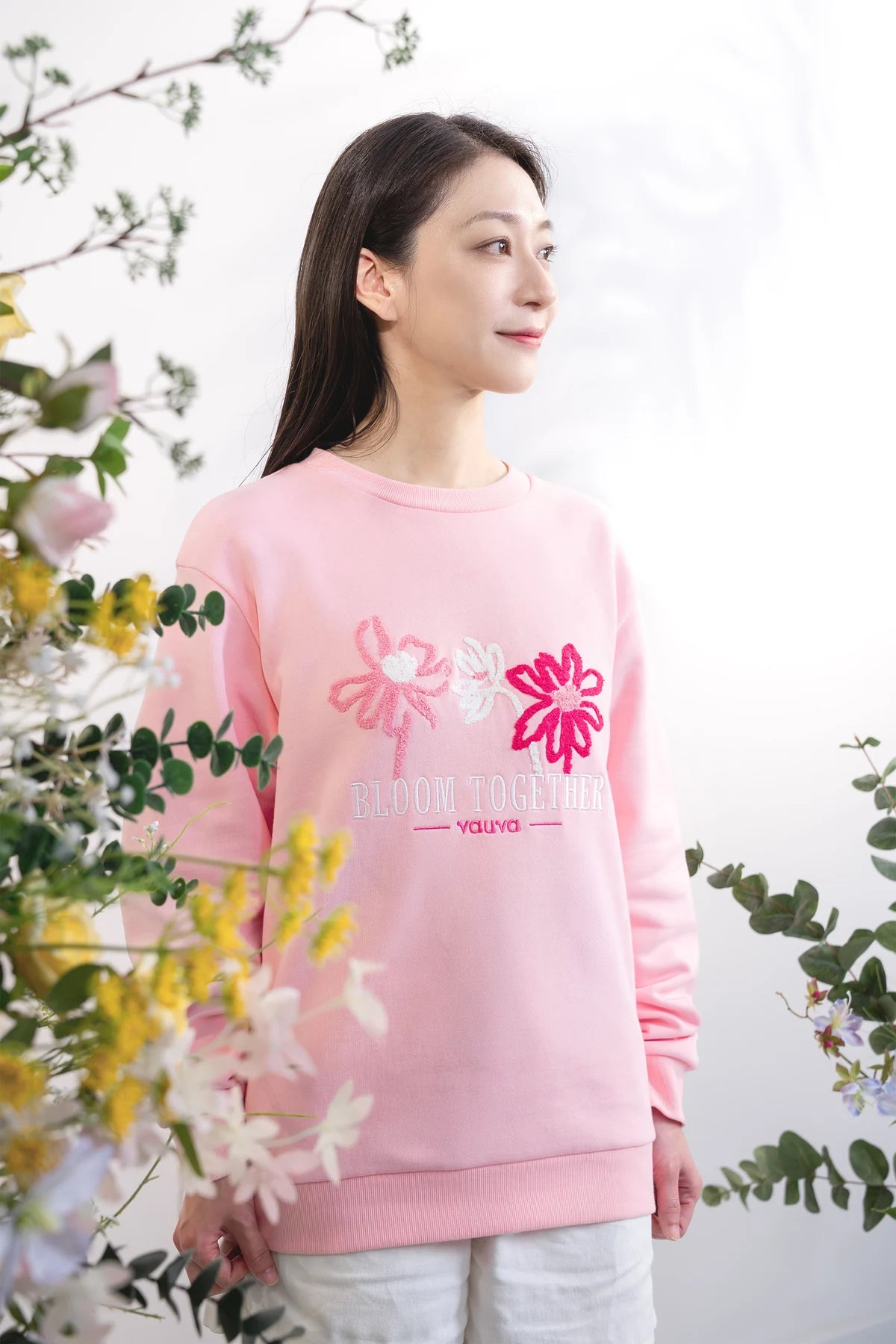 Adult wearing a pink Bloom Together embroidered sweatshirt.
