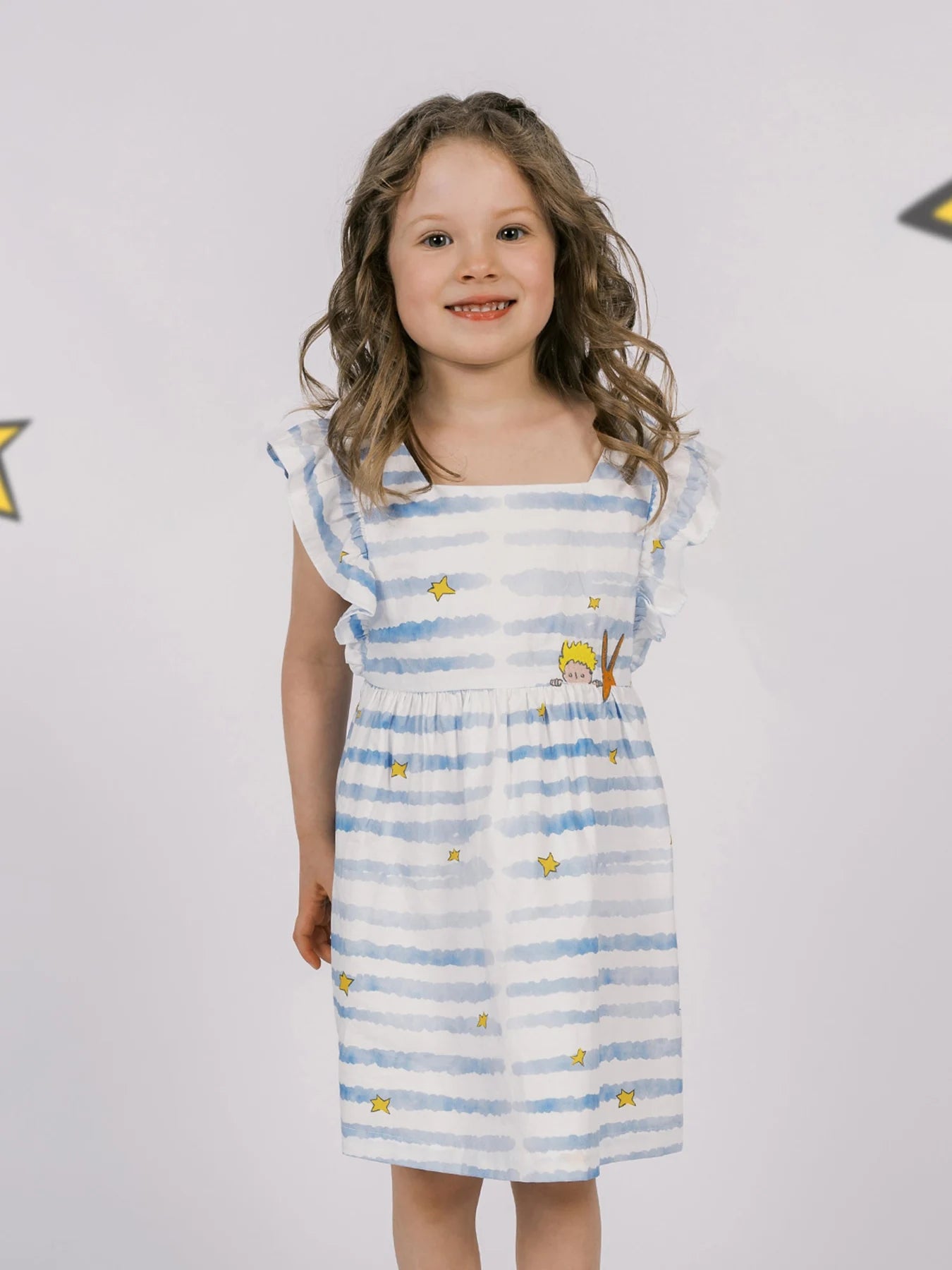 Blue brushstroke stripes and yellow stars run through the ruffled dress.