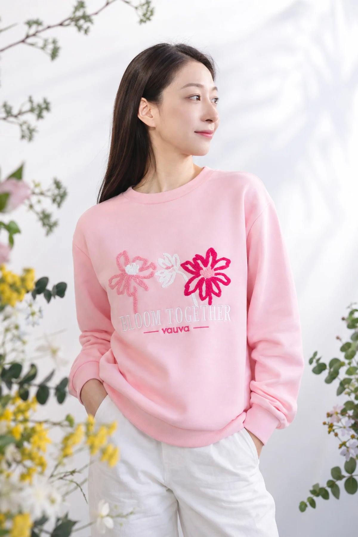 Adult in a blush-pink sweatshirt with embroidered flowers.
