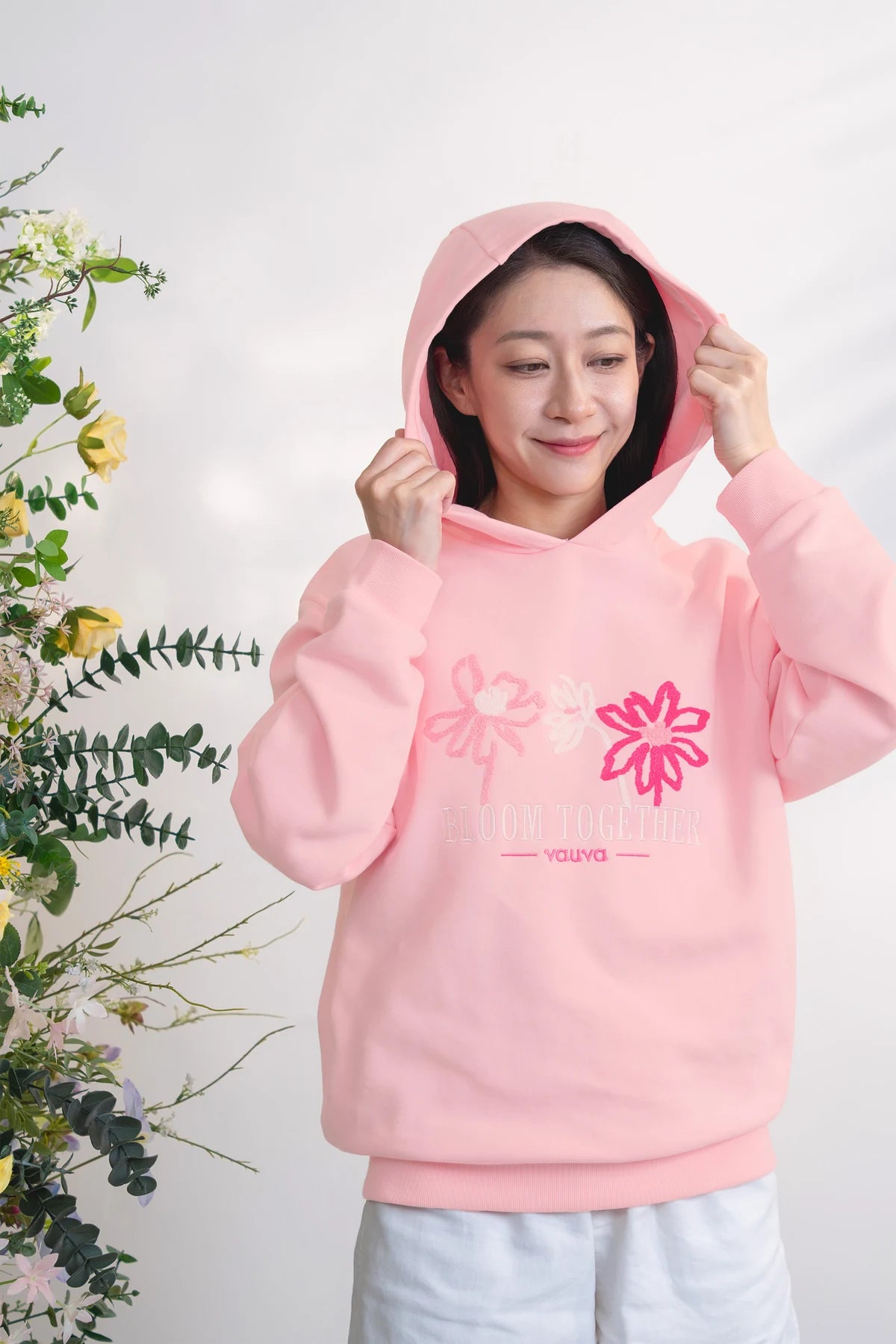 Adult wearing the pink embroidered hoodie.