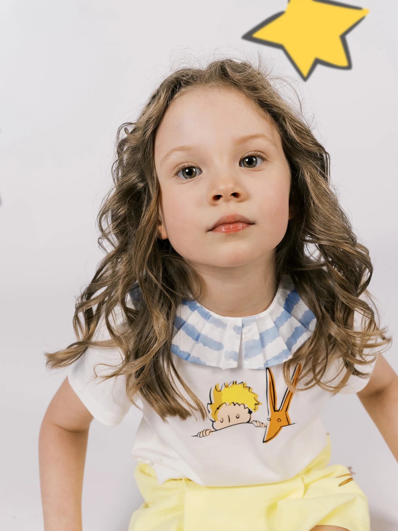 Portrait showing the white Le Petit Prince tee and its star-printed pleated collar.