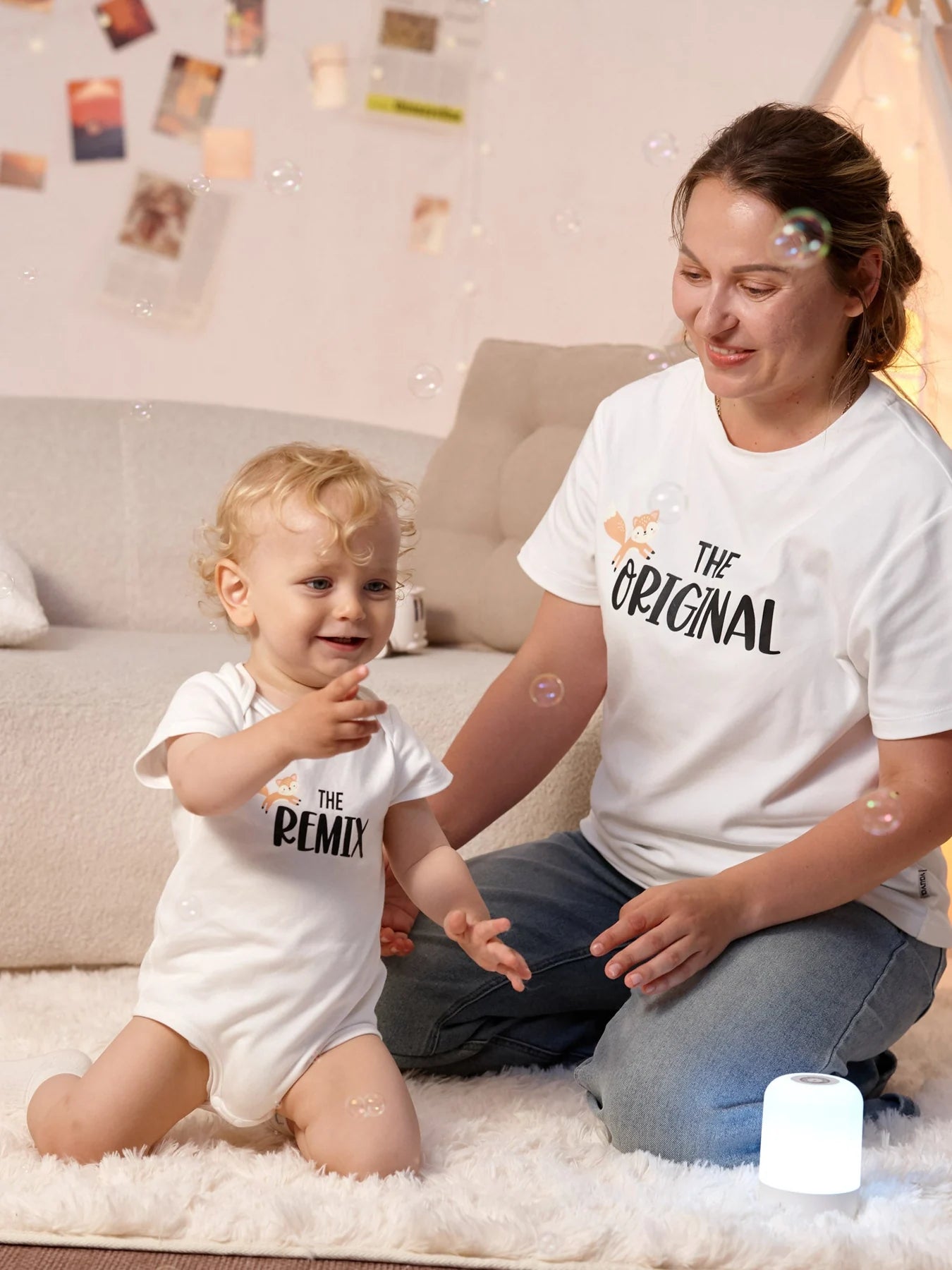 Adult in The Original white tee sits beside a baby in The Remix white bodysuit.
