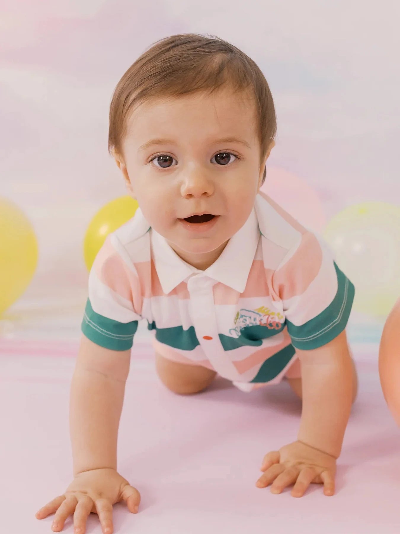 Baby crawling in the green and pink striped shortie romper.