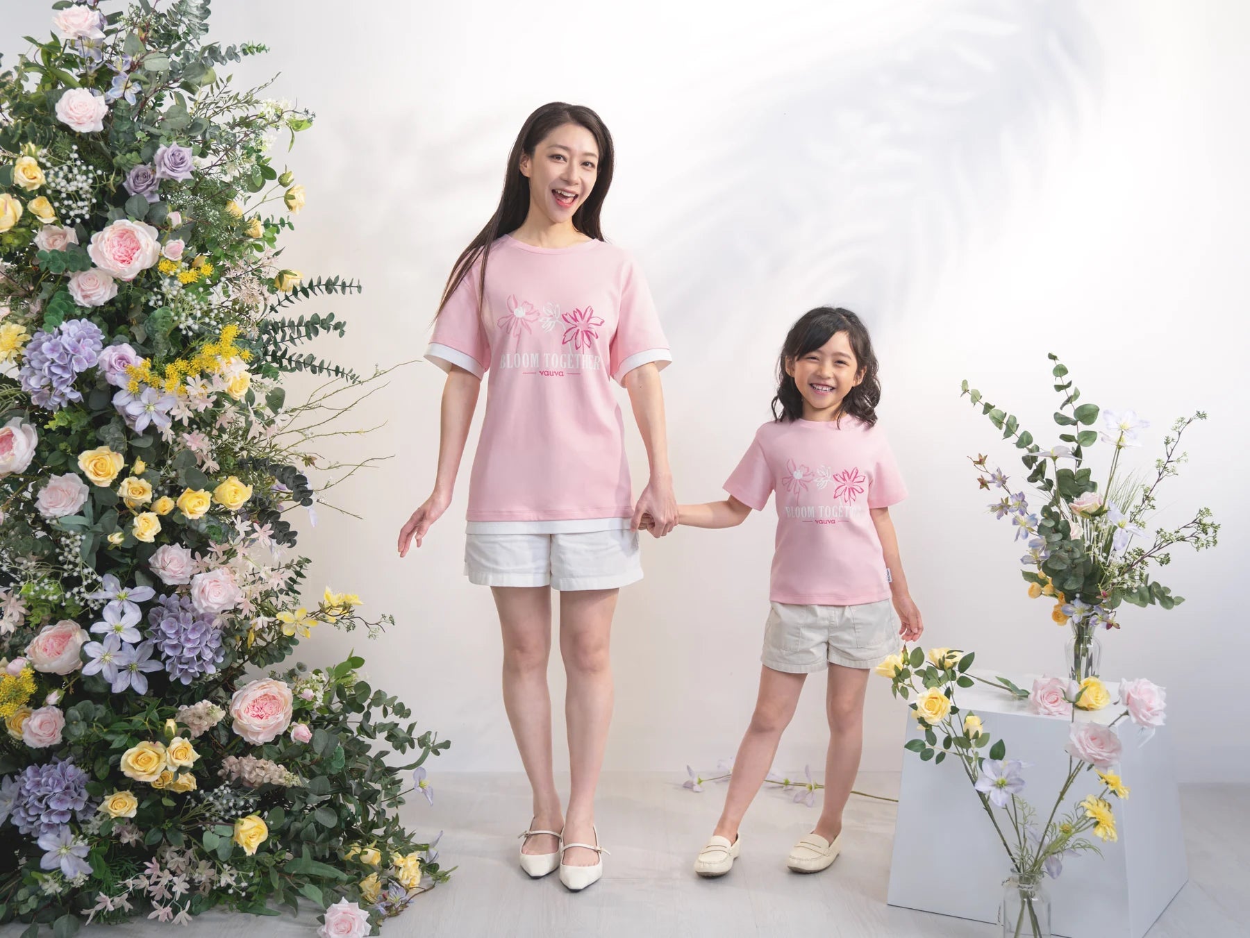 A child and grown-up wear coordinating pink Bloom Together printed tees.