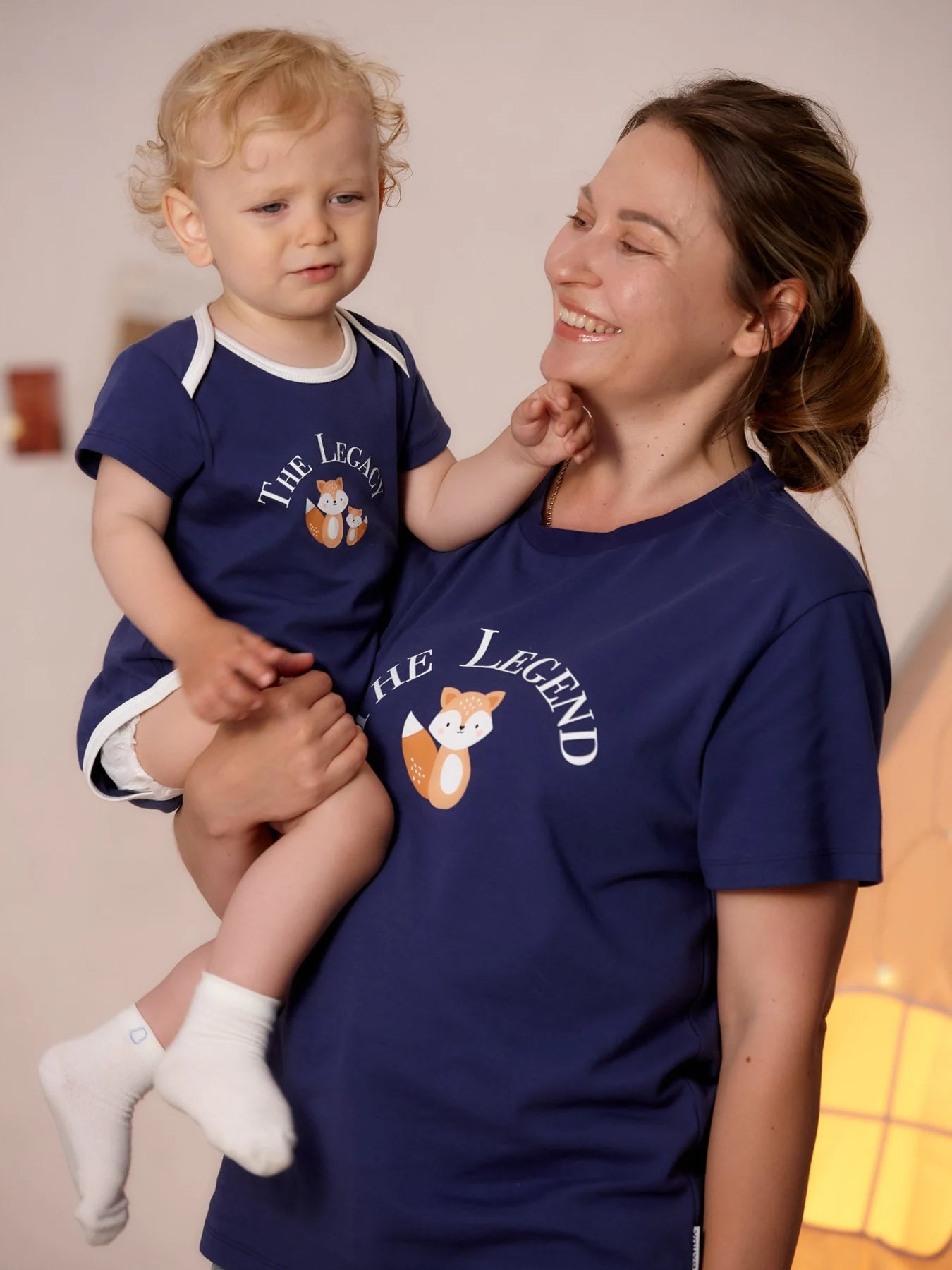Parent holding a baby in the navy The Legacy bodysuit.