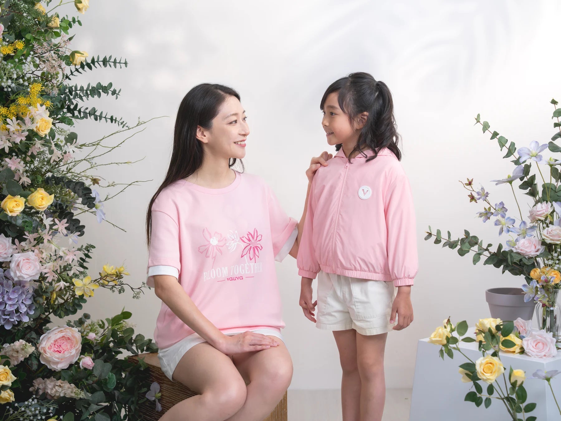 Adult in a layered pink tee sits beside a child in the pink jacket.