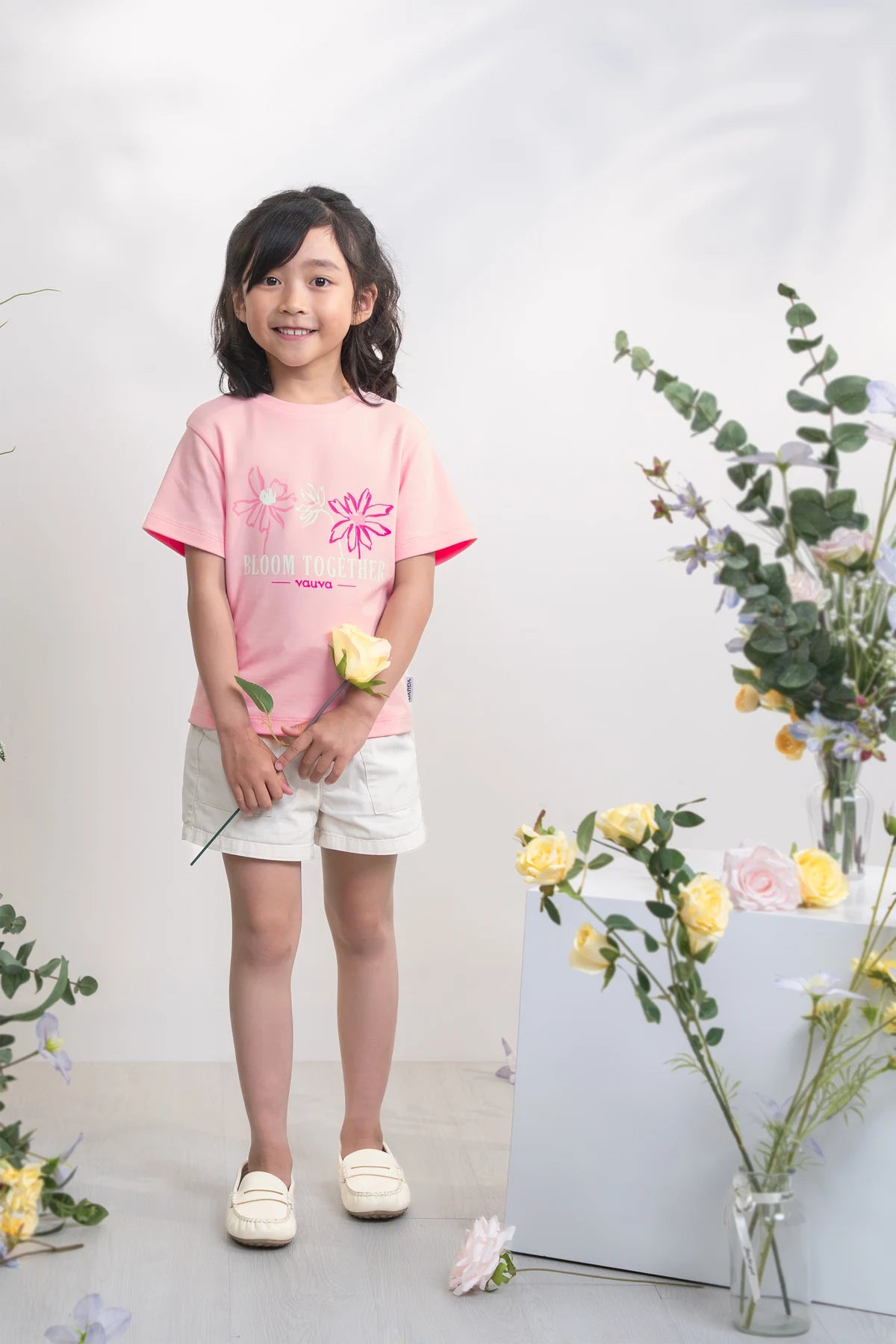 Child in a pink floral graphic tee, with white shorts used for styling.