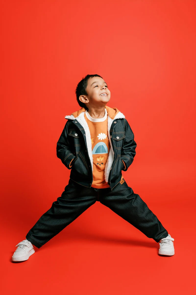 A child striking a playful pose in a dark jacket and trousers. Face of Vauva 2025.