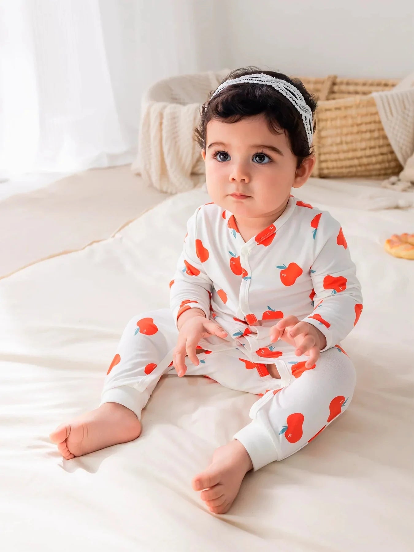 Baby wearing an apple-print BBNS romper.