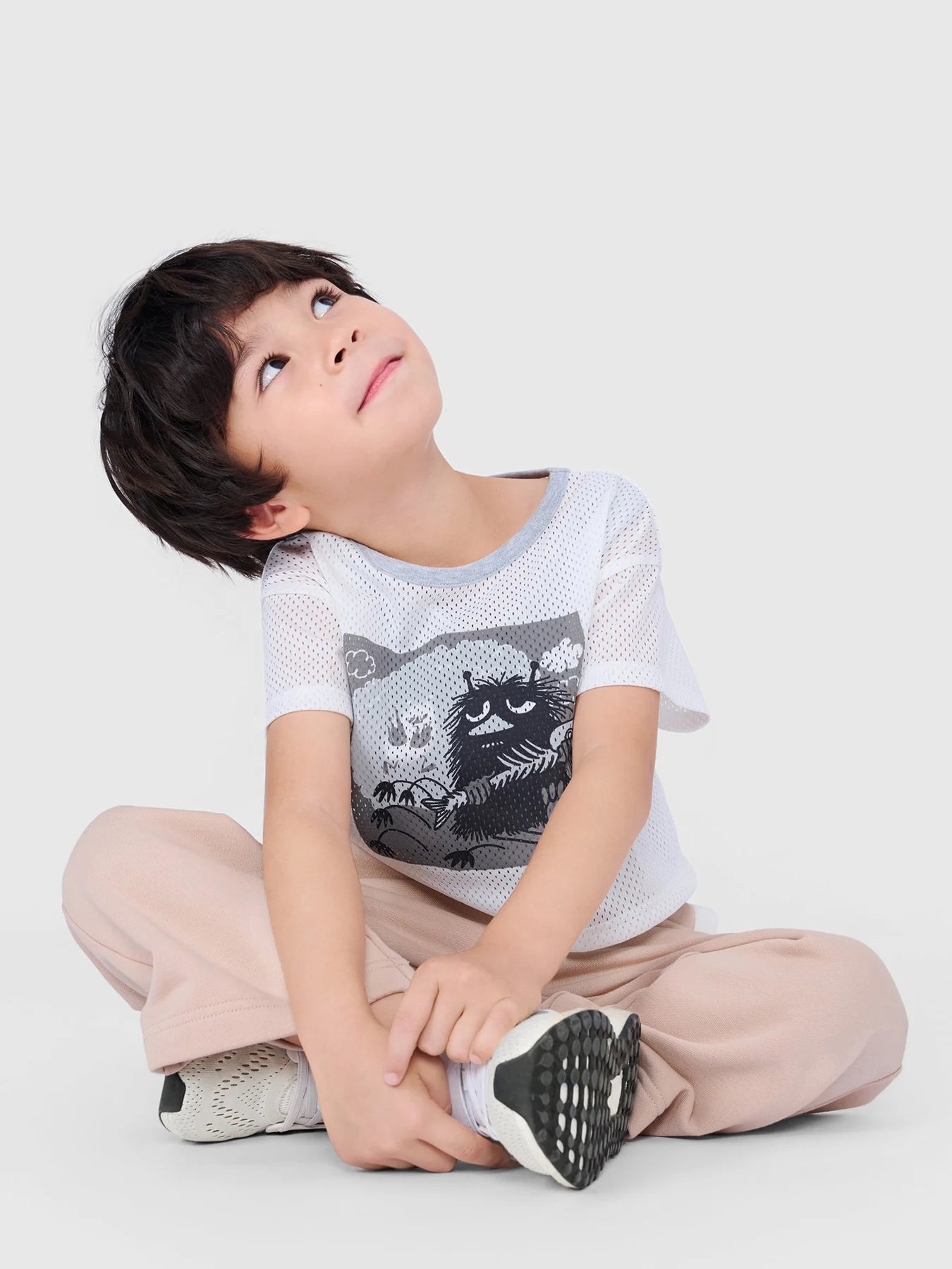 Boy looking upward while seated in the grey Stinky layered mesh T-shirt set.