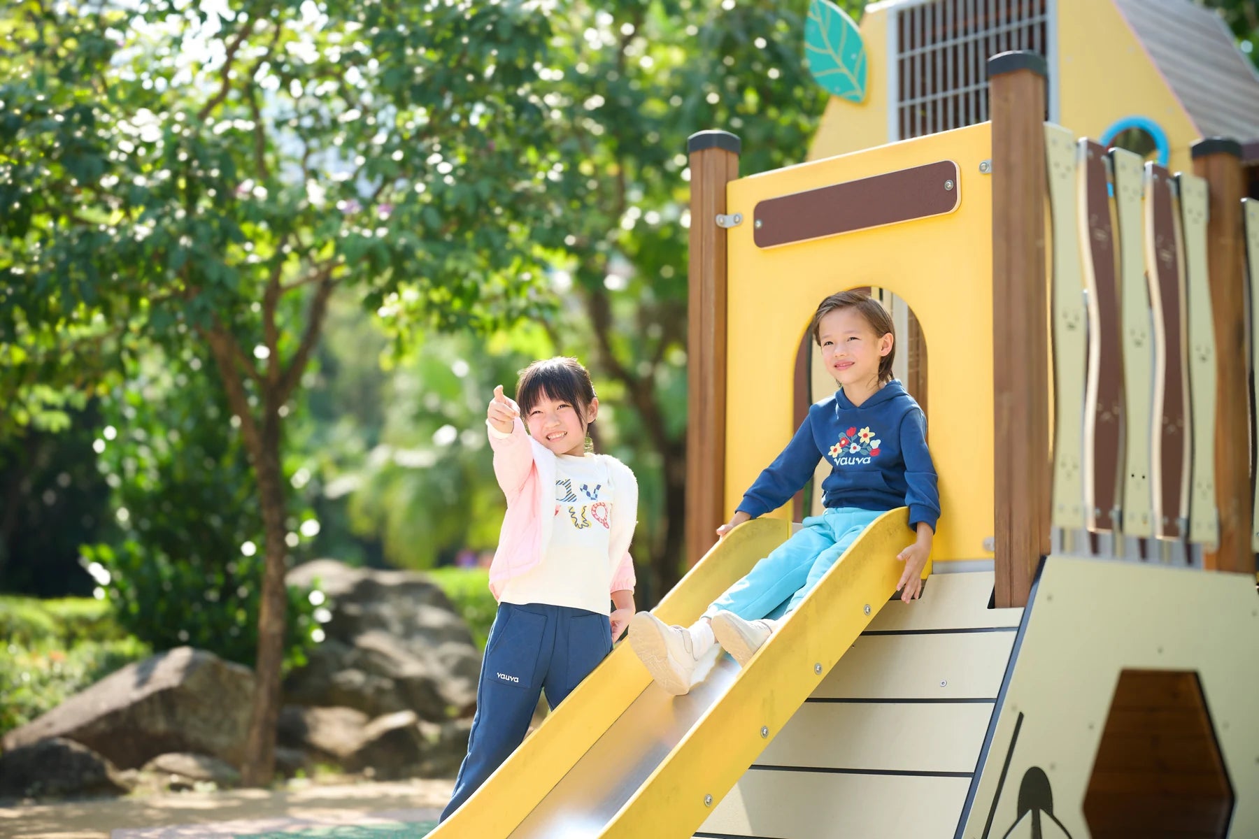 Two children playing together on a wooden playground in Vauva FW26.