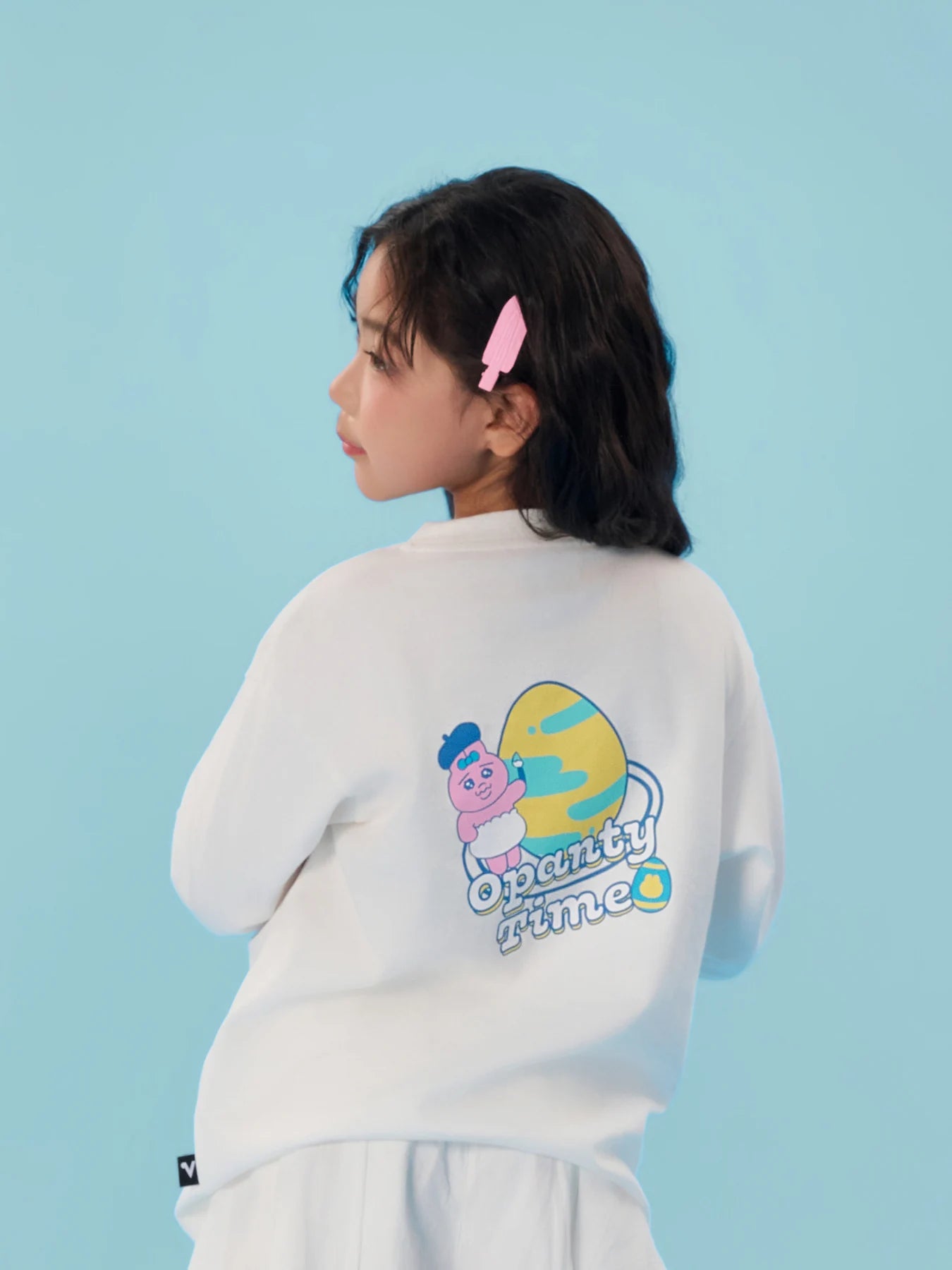 Back of the white long-sleeve Opanchu tee showing colourful egg and bunny artwork.