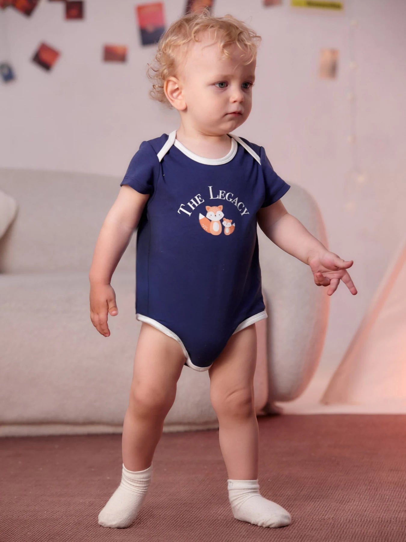 Baby wearing the navy The Legacy bodysuit with white trim.