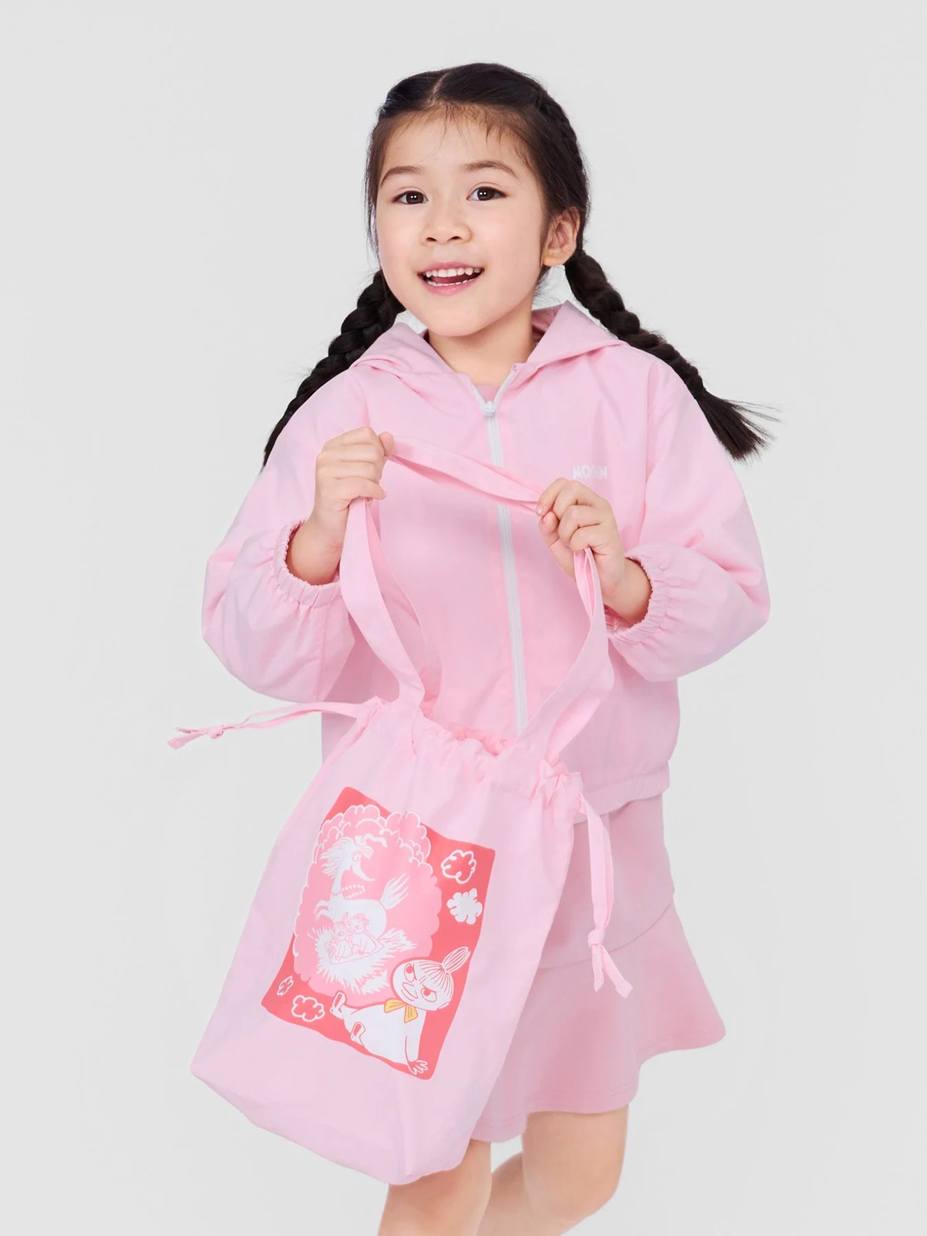 Girl carrying the pink Little My drawstring tote with her matching jacket.