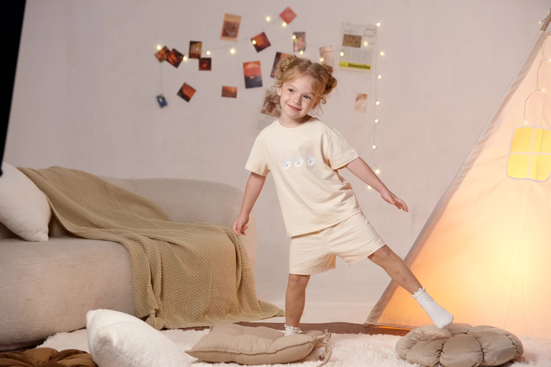 A child in the beige bunny T-shirt and coordinating shorts, stepping beside a low table.