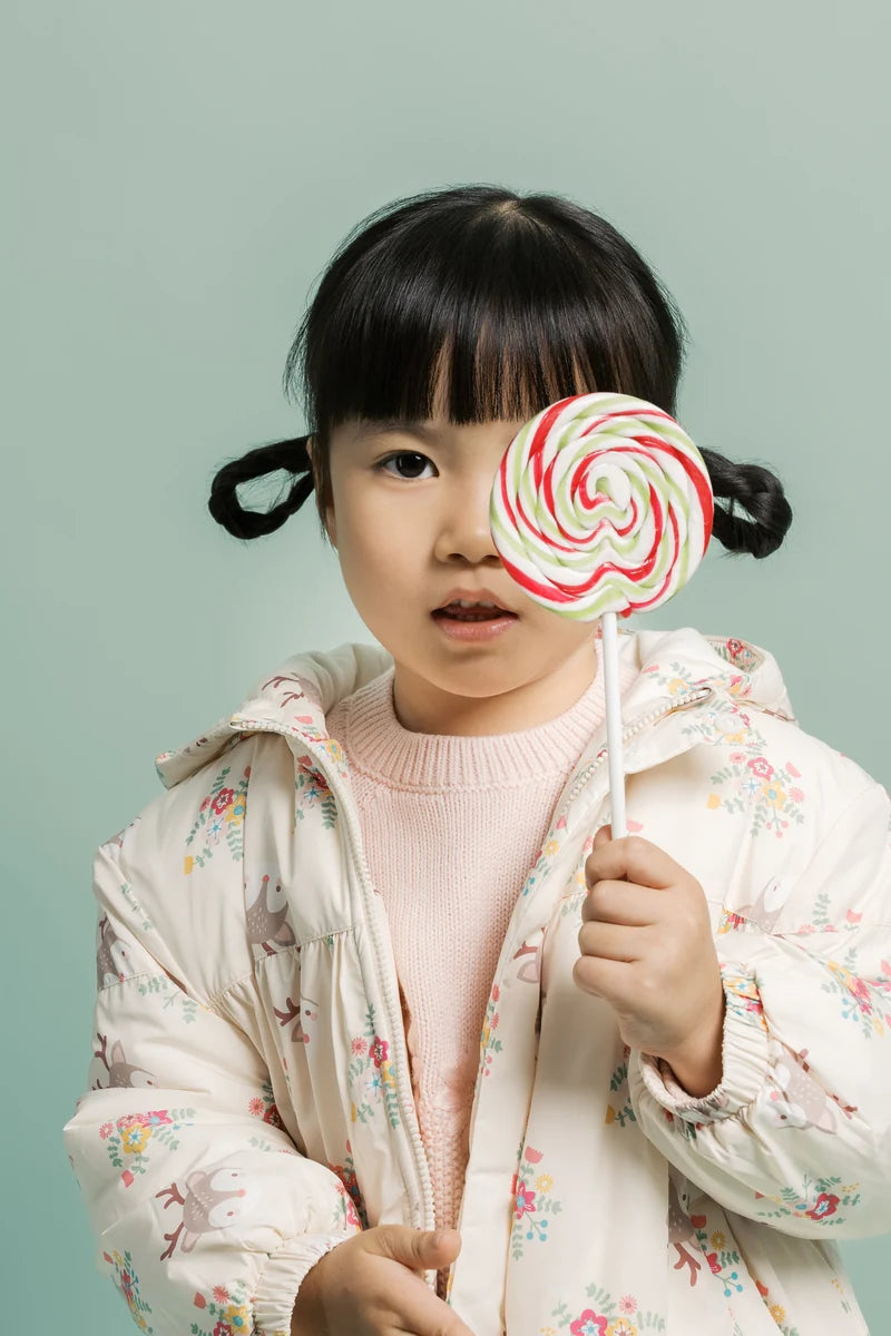 A child holding a colourful lollipop. Face of Vauva 2025.