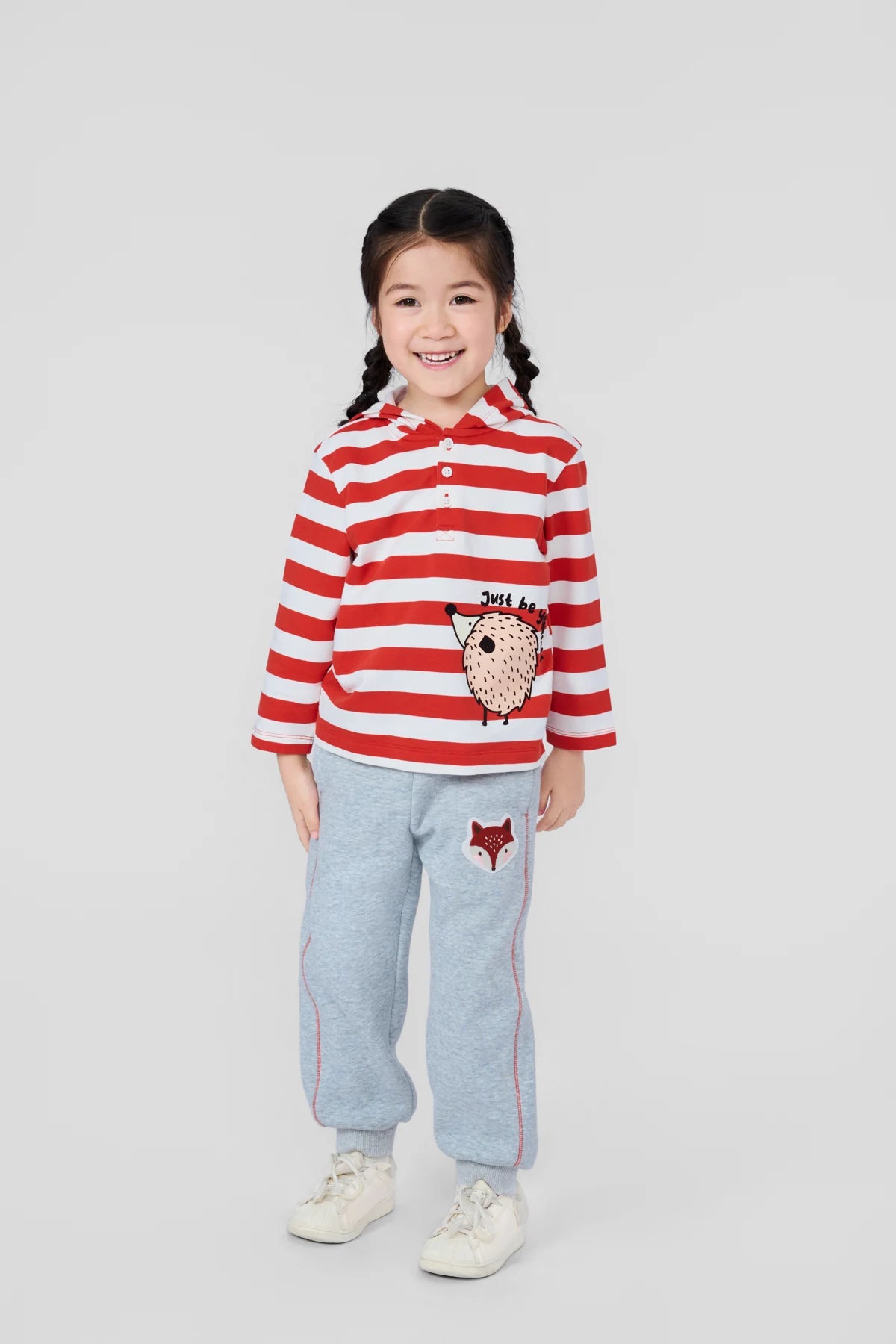 Girl wearing the red striped hedgehog hooded Henley and grey fox patch joggers.