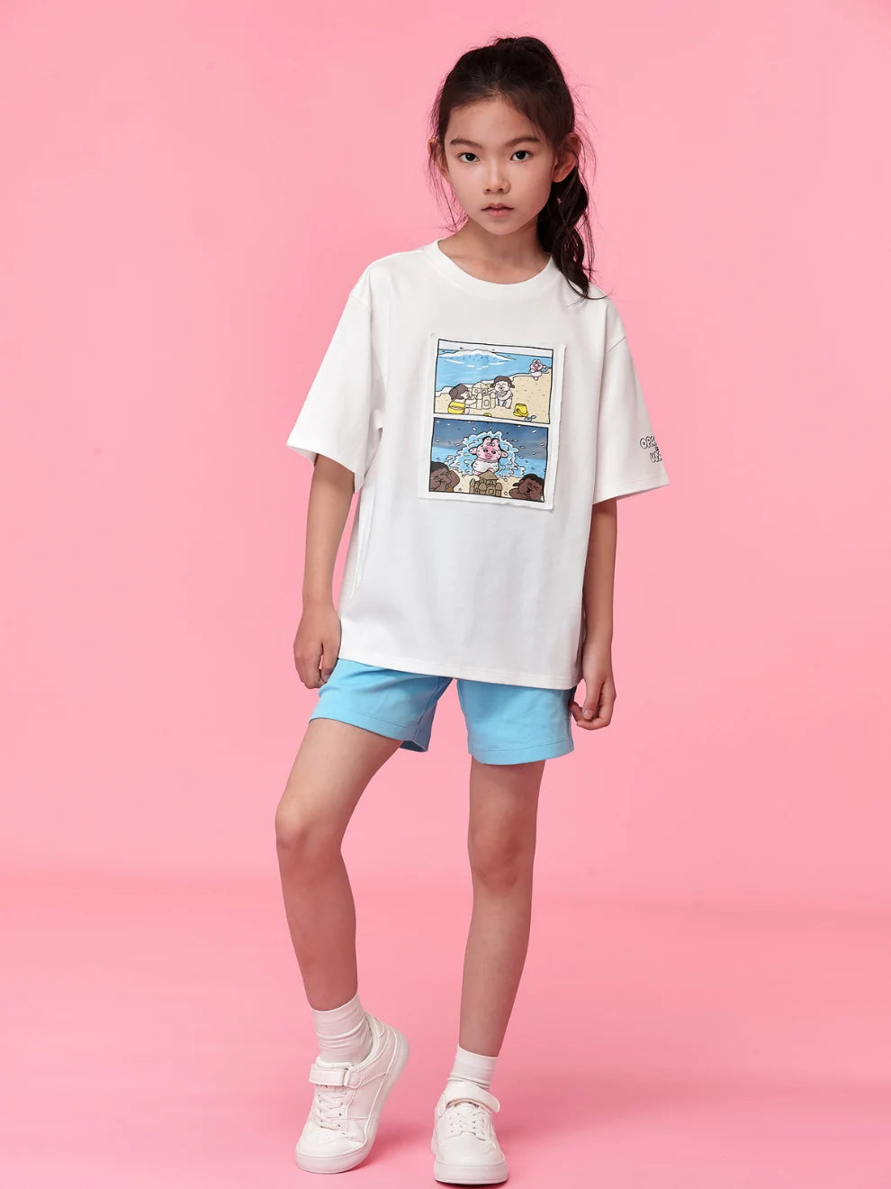 Girl wearing the white Summer Day comic-print tee against a pink studio background.