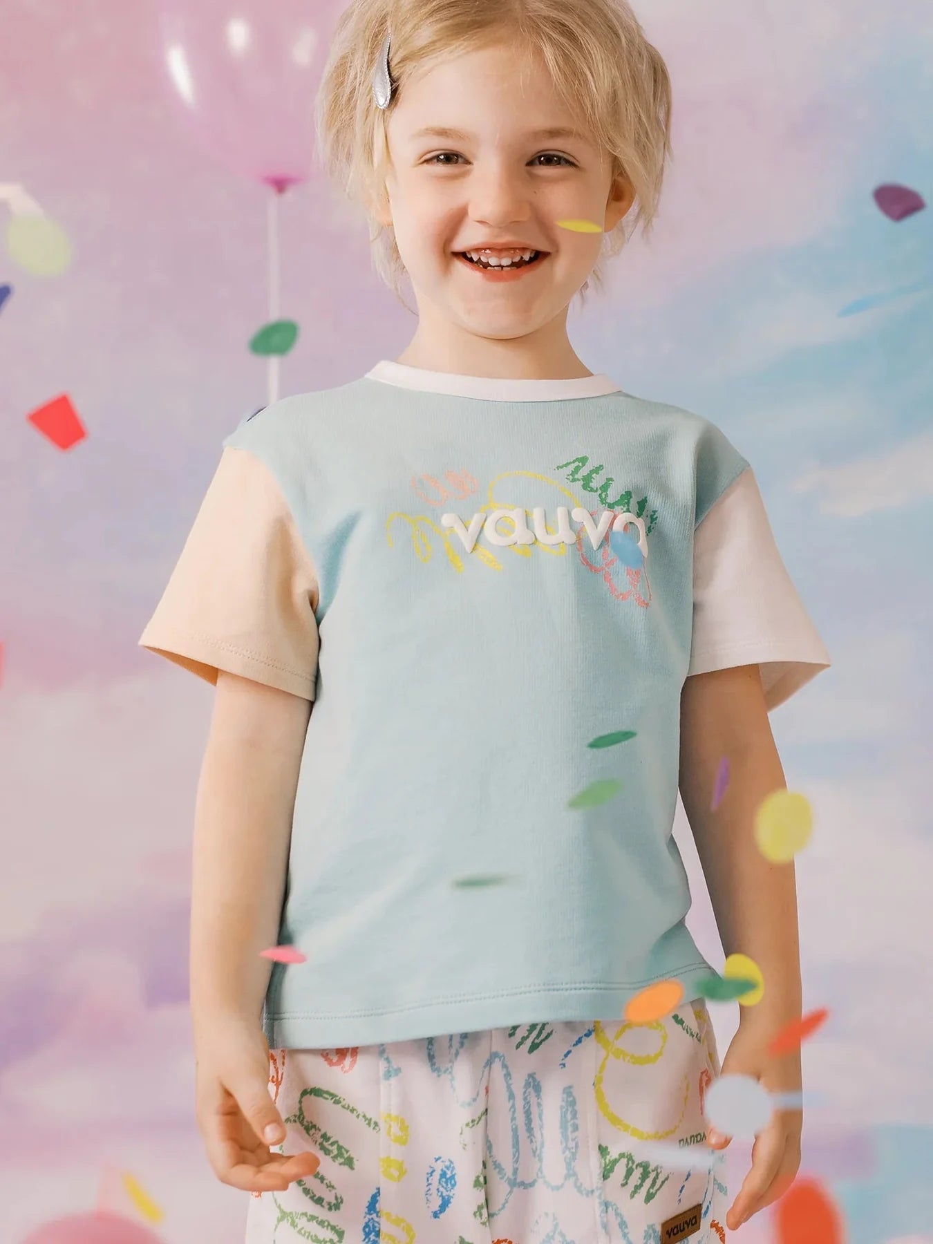 Smiling child wearing the mint colour block Vauva tee.