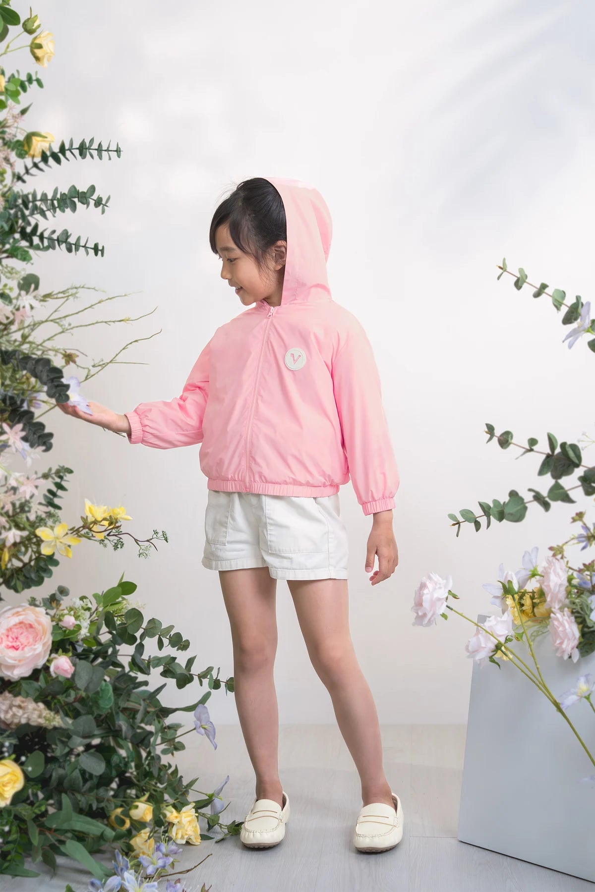 Child in the pink hooded windbreaker with floral back print.